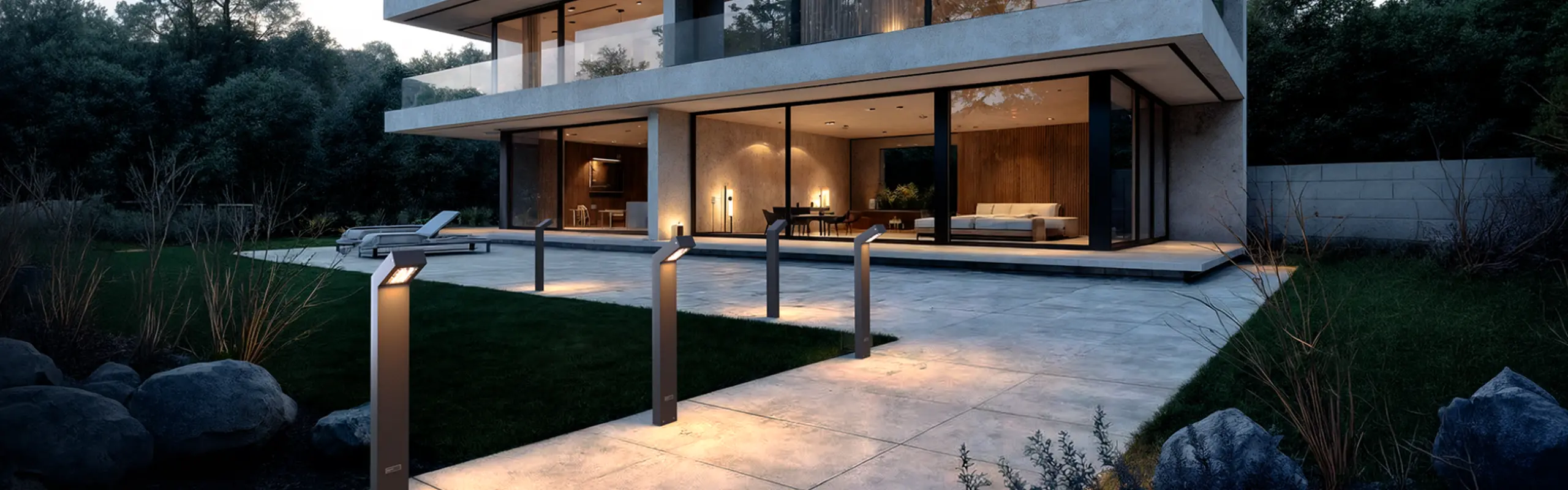 Alacakaranlıkta modern bir evde havuz kenarı patikasını aydınlatan bir sıra Fonelight bollard armatürü