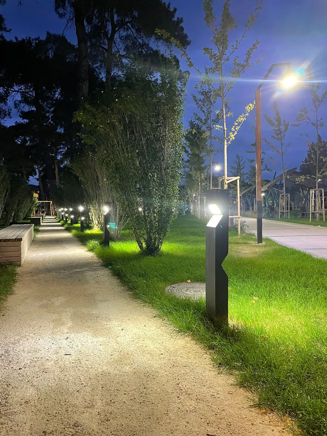 Geceleyin aydınlatılmış, bir sitenin içindeki yürüyüş yolu boyunca bollard armatürler